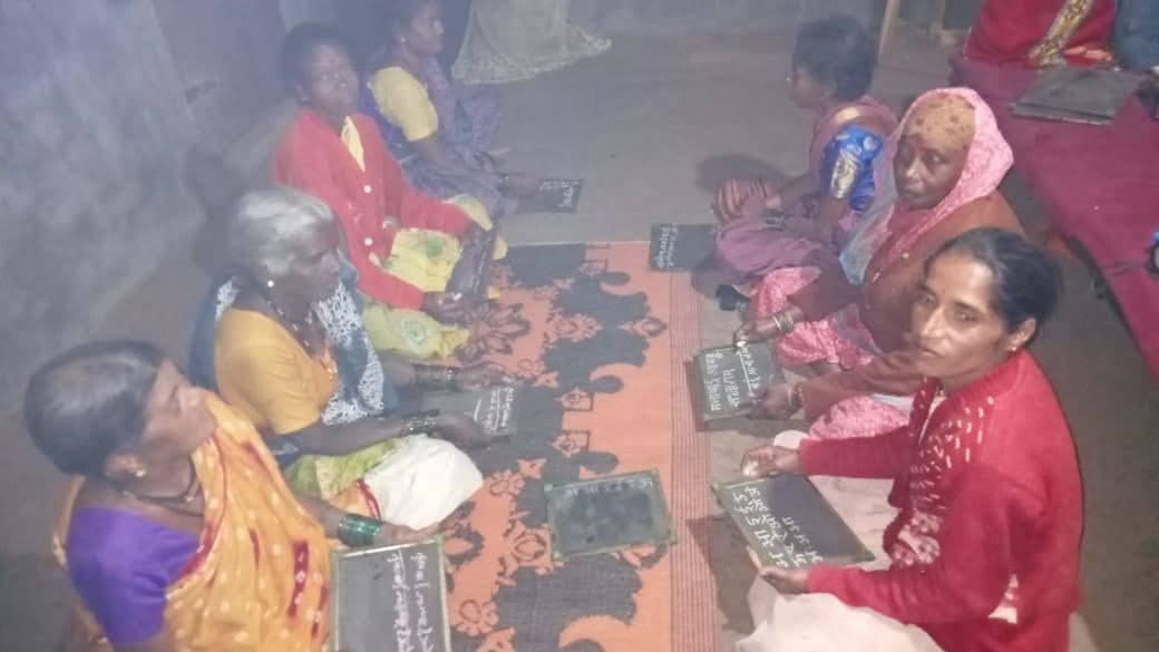 Women writing on slates at the club's adult literacy class
